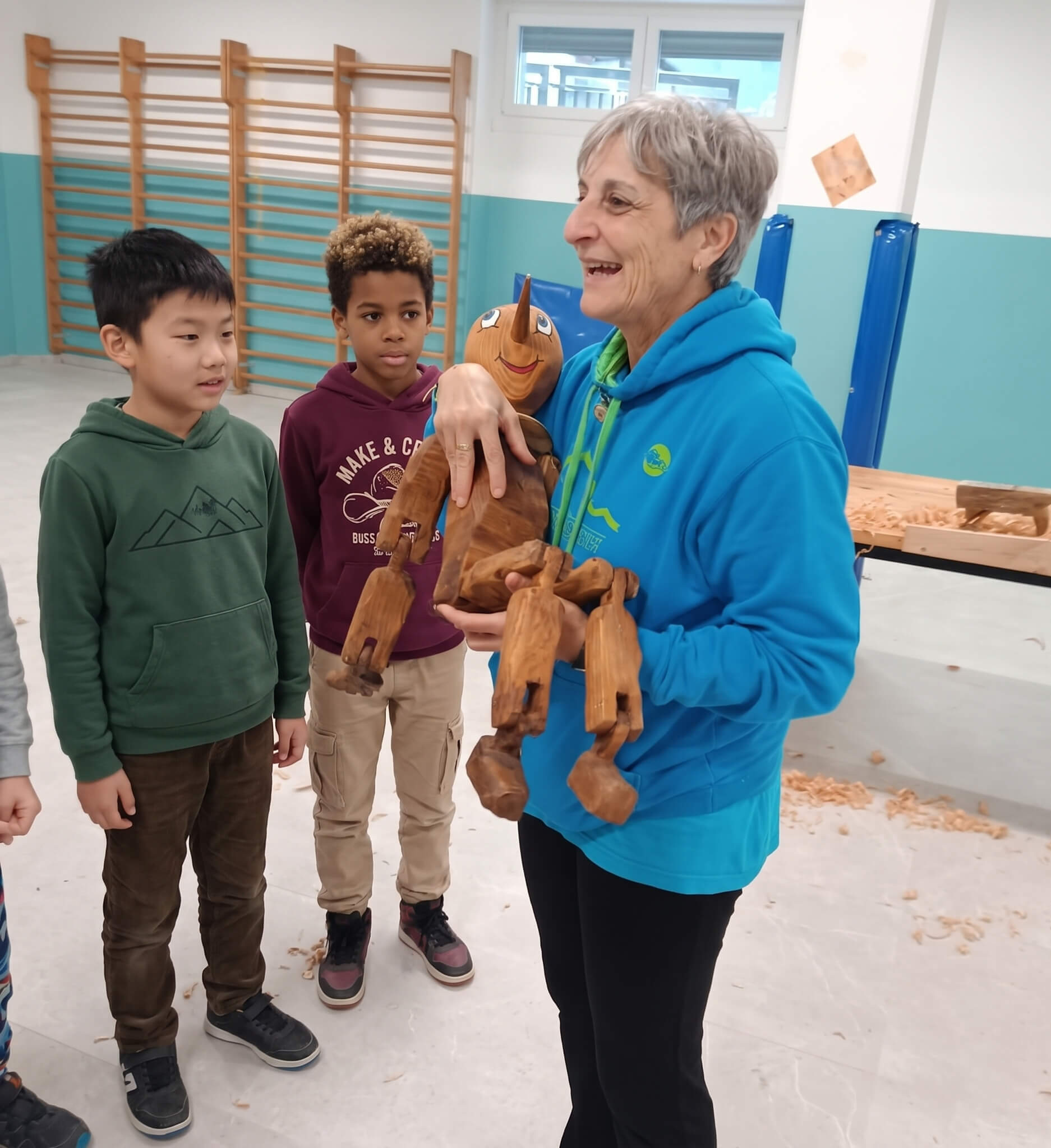 Educatrice che mostra un burattino in legno ai bambini durante un momento dimostrativo del laboratorio.