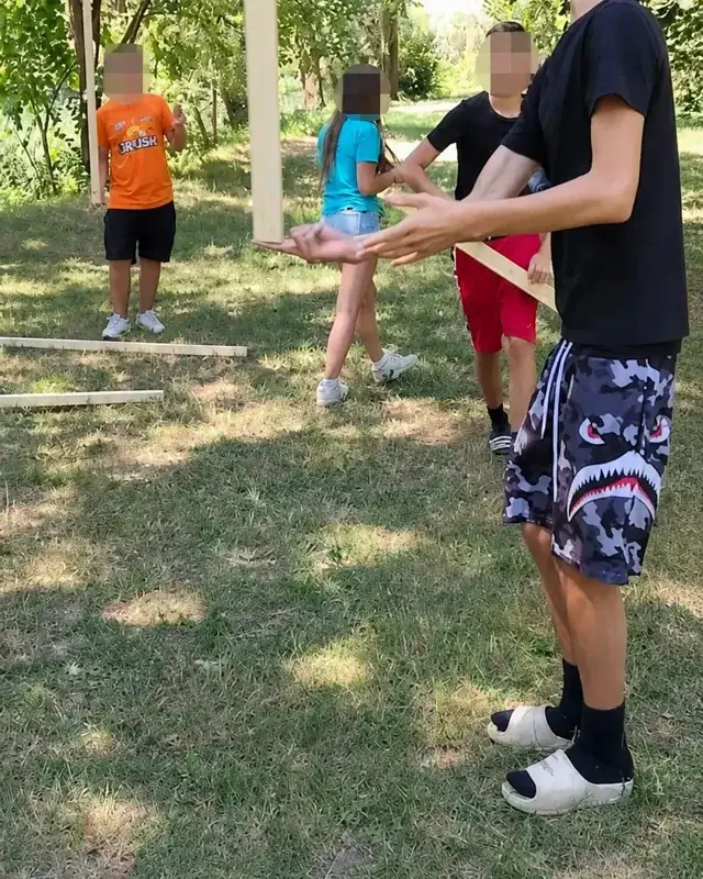 Una squadra di ragazzi è riunita all’aperto intorno a una costruzione di legno.