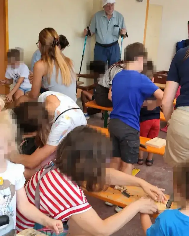 Molti partecipanti lavorano attorno ai tavoli del laboratorio di falegnameria.