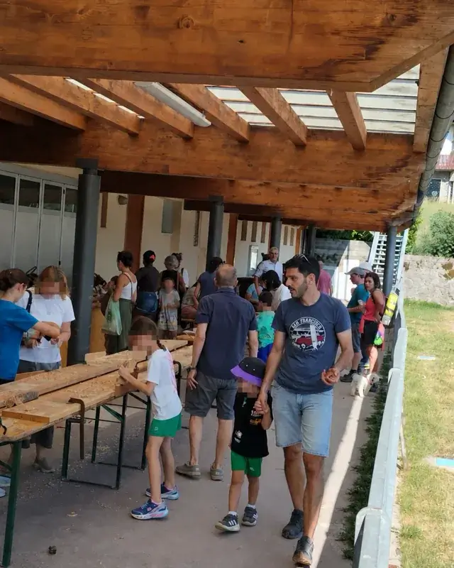 Partecipanti in movimento tra i lunghi banchi del laboratorio sotto il portico.