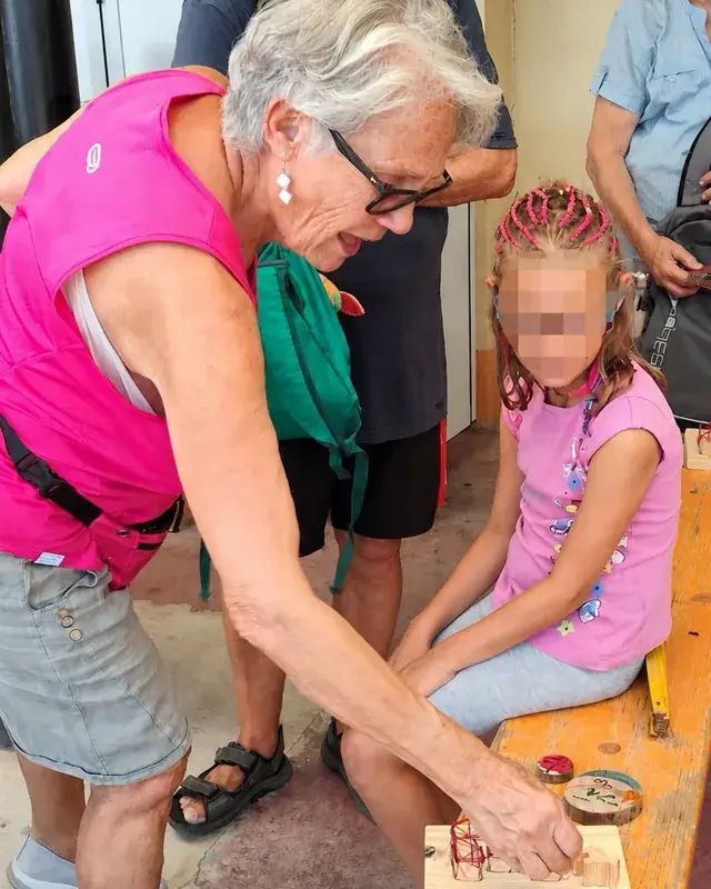 Una donna e una bambina lavorano insieme a una piccola costruzione di legno.