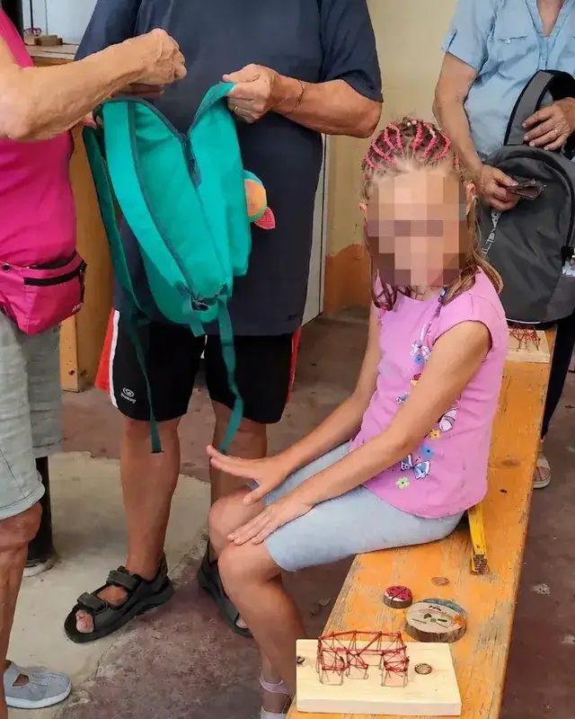 Una bambina mostra un piccolo lavoro di legno accanto agli adulti.