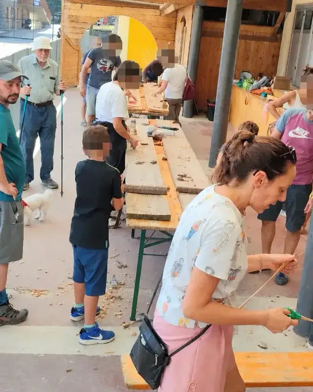 Vista generale dei tavoli di falegnameria con bambini e adulti al lavoro.