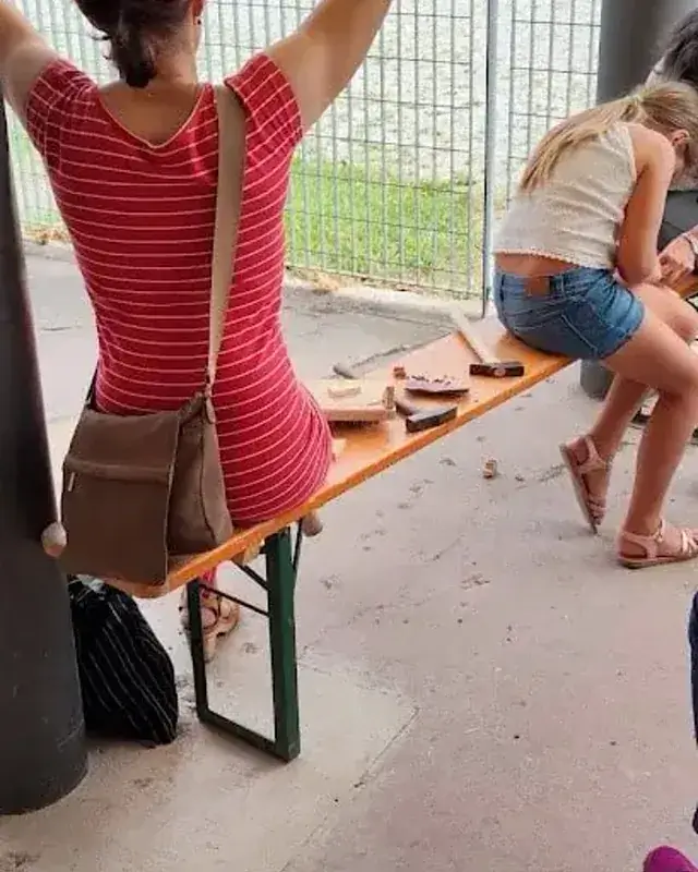 Due partecipanti ripresi di lato mentre lavorano su piccoli pezzi di legno.
