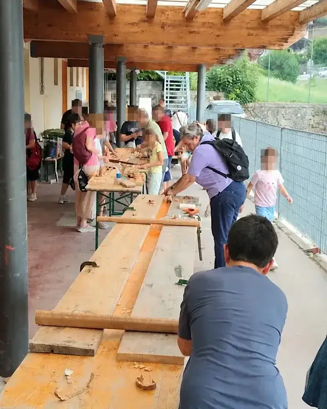 Più gruppi lavorano il legno lungo lo stesso banco di falegnameria.