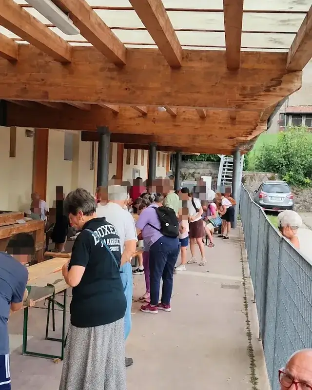 Bambini e adulti riuniti al banco durante il laboratorio di falegnameria.