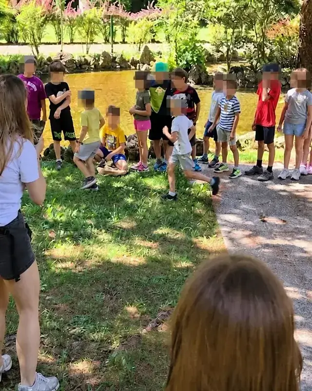 Un gruppo è riunito sul prato sotto gli alberi per l’attività nel parco.