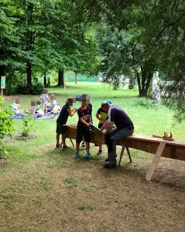 Un piccolo gruppo lavora al banco sotto gli alberi del parco.